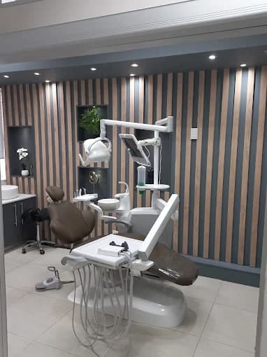 A treatment room at the Umhlanga Ridge practice, with a dental chair and overhead light against a vertical timber-slat wall.